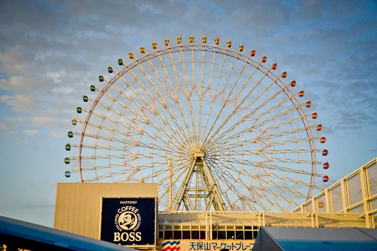 The Tempozan Ferris Wheel, ringed with spokes and coloured cars, against a blue sky with cloud